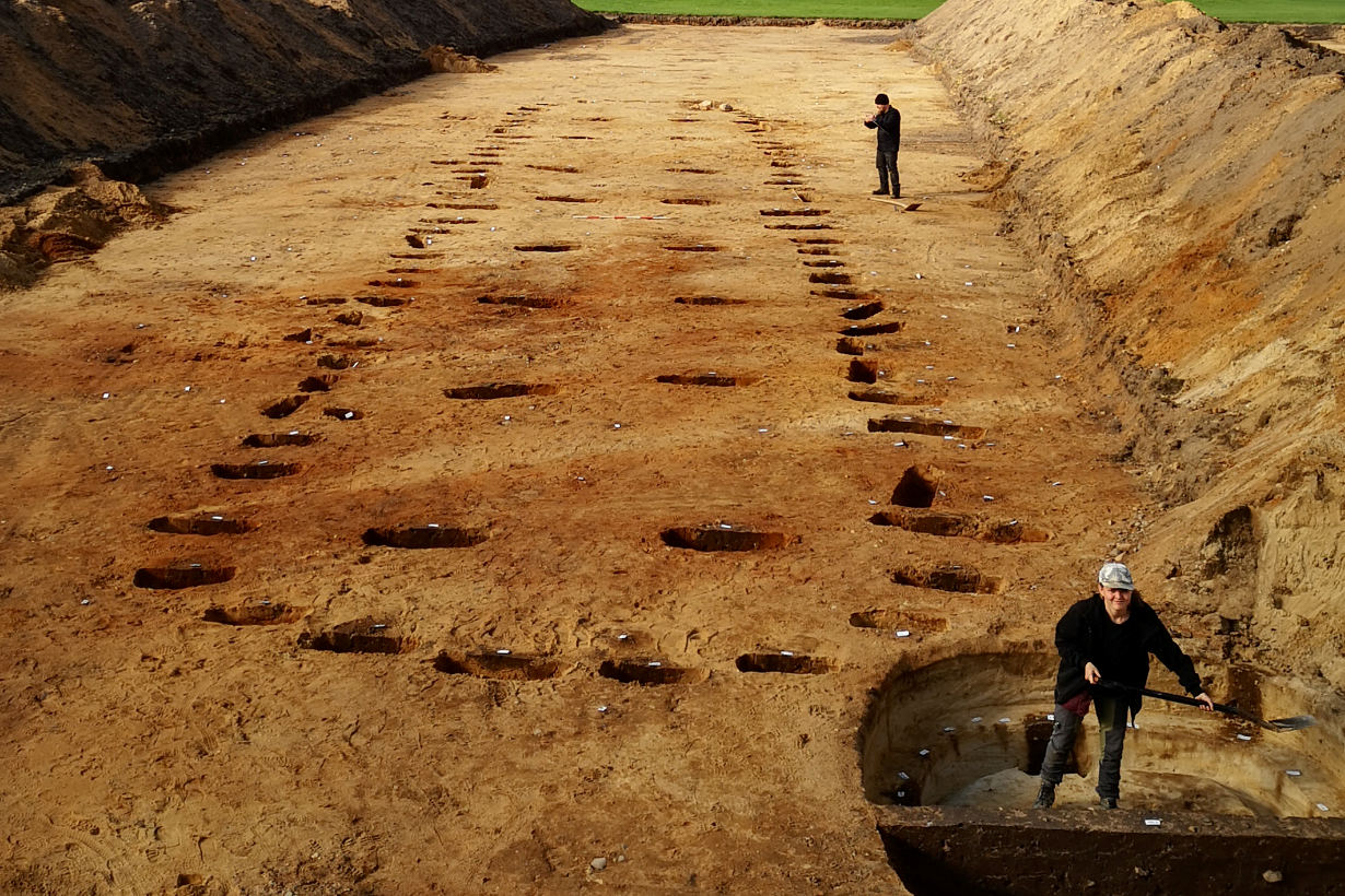 Arkæologerne ved et felt med stolpehuller fra et stort hus